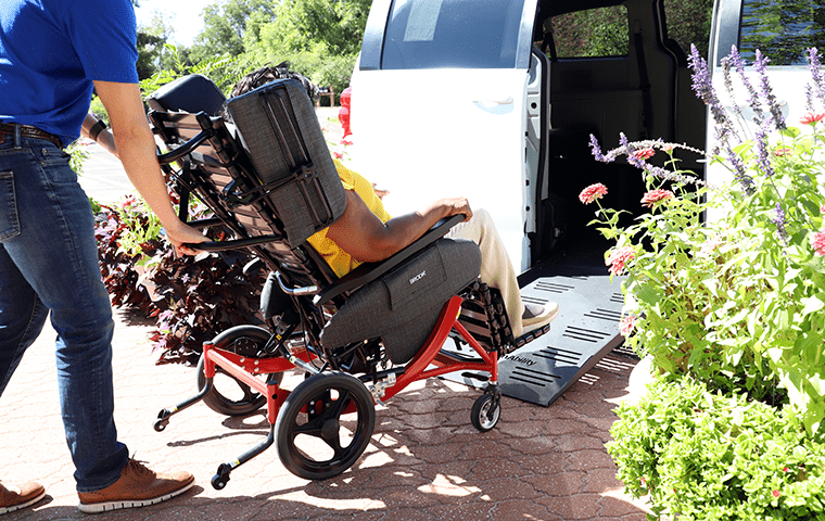 Wheelchair passenger rolling up the ramp onto a white minivan