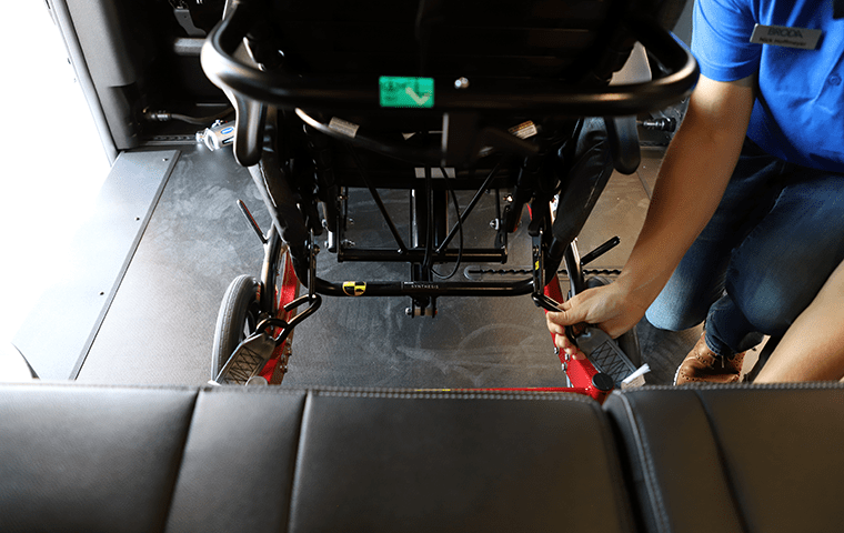 Man securing wheelchair to the floor of a minivan