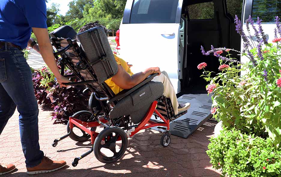 A Woman in a Synthesis chair being loaded into a NEMT vehicle