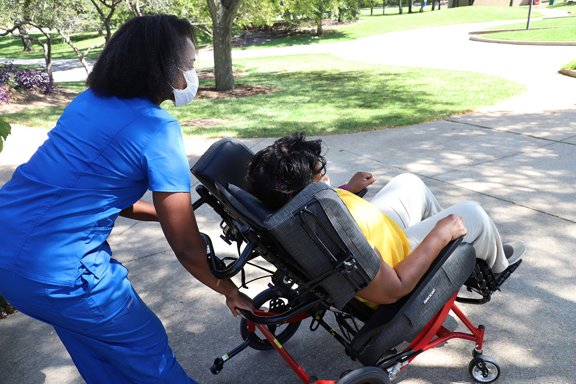 Nurse tilts a wheelchair for the woman seated in the wheelchair