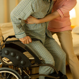 Hospice Worker Assisting Elderly Man Into A Wheelchair
