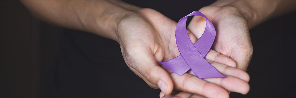 Close-up of hands holding a cancer awareness ribbon