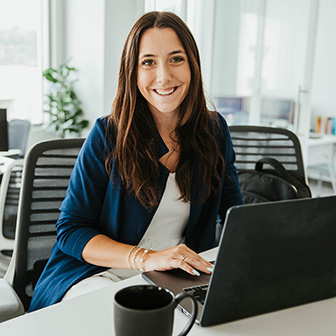 A woman in an office setting working on a laptop