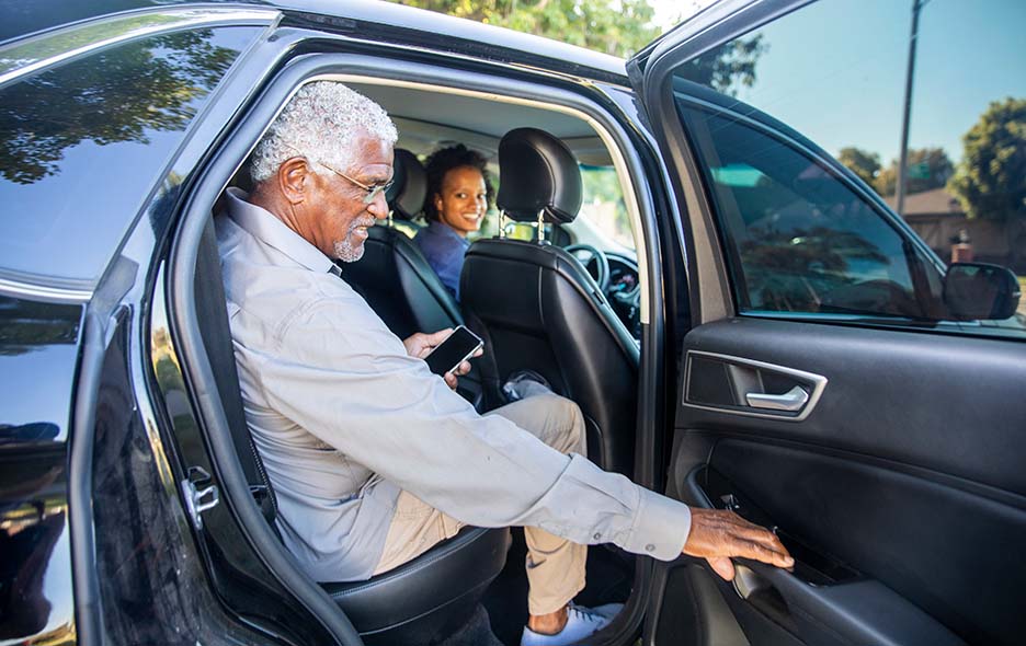 senior gentleman getting into the back seat of a vehicle