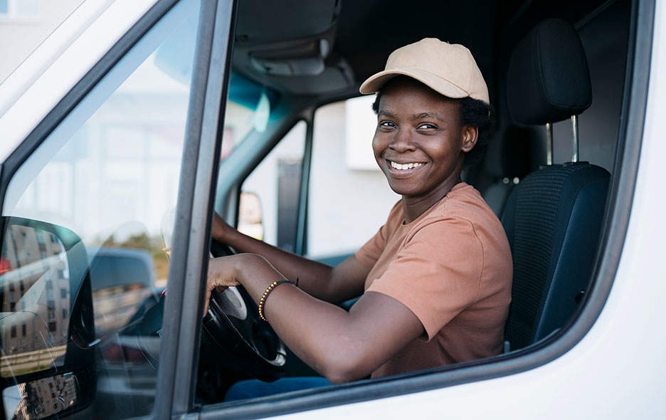 Driver smiling from the front seat of a transport van