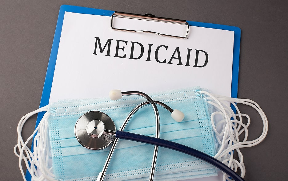 A clipboard with Medicaid forms, a mask, and stethoscope