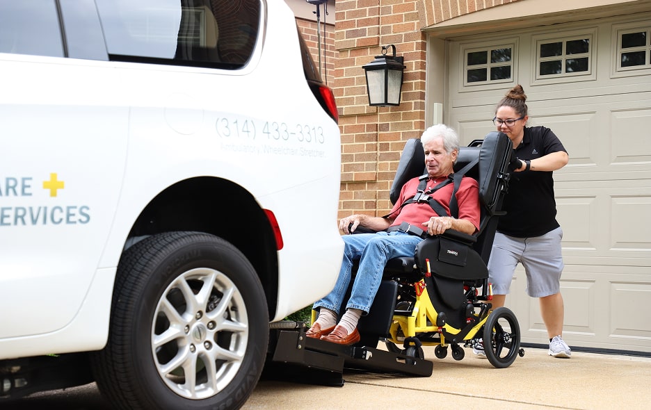 An NEMT driver is wheeling a patient into the back of a minivan