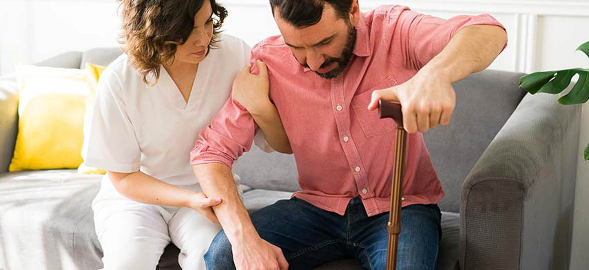 Young man with a cane standing up with a nurse at his side