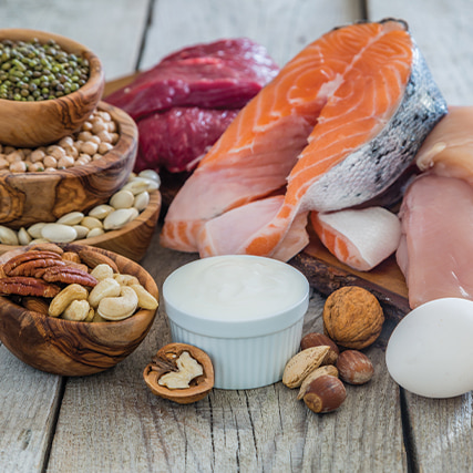 A close-up look at an arrangement of various protein sources resting upon a tabletop: nuts, fish, etc.