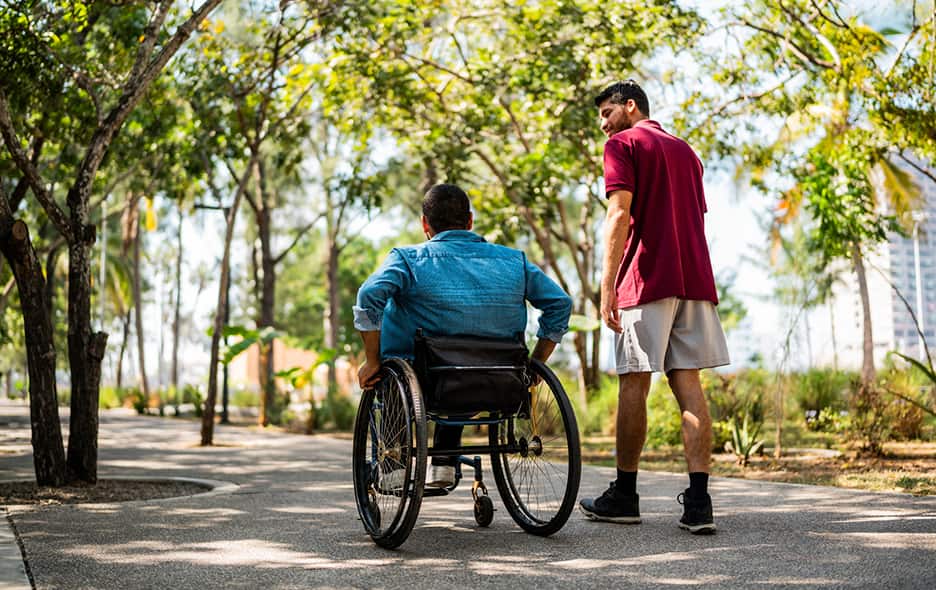 A person in a wheelchair enjoying time in the park with their friend