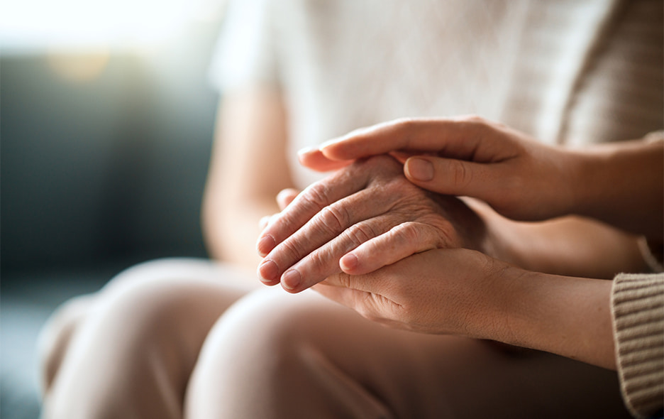 Close up of clasped hands rested upon someone's lap